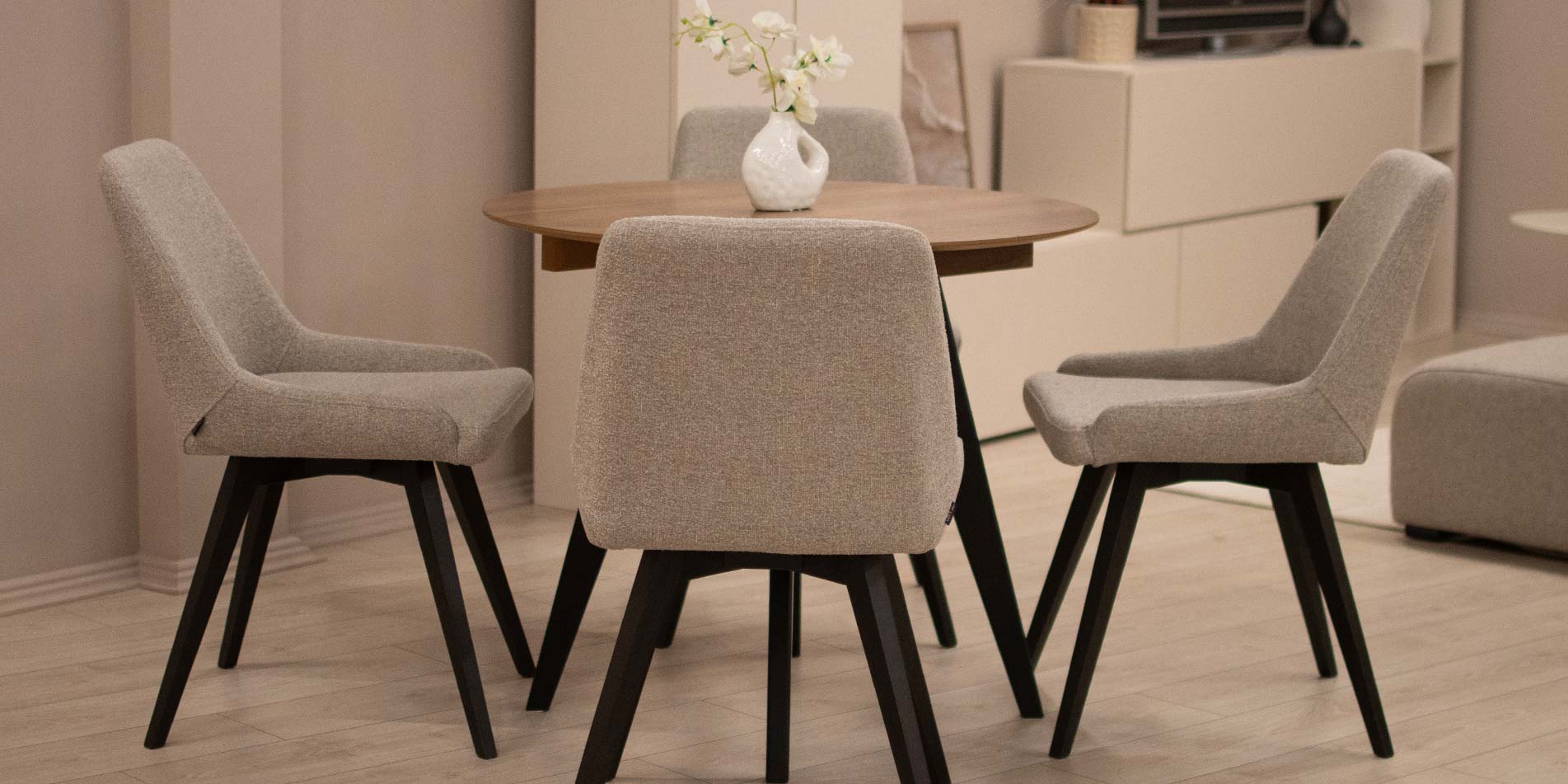 Trpezariska stolica Naomi so crni drveni nogarki na mala kruzna masa.