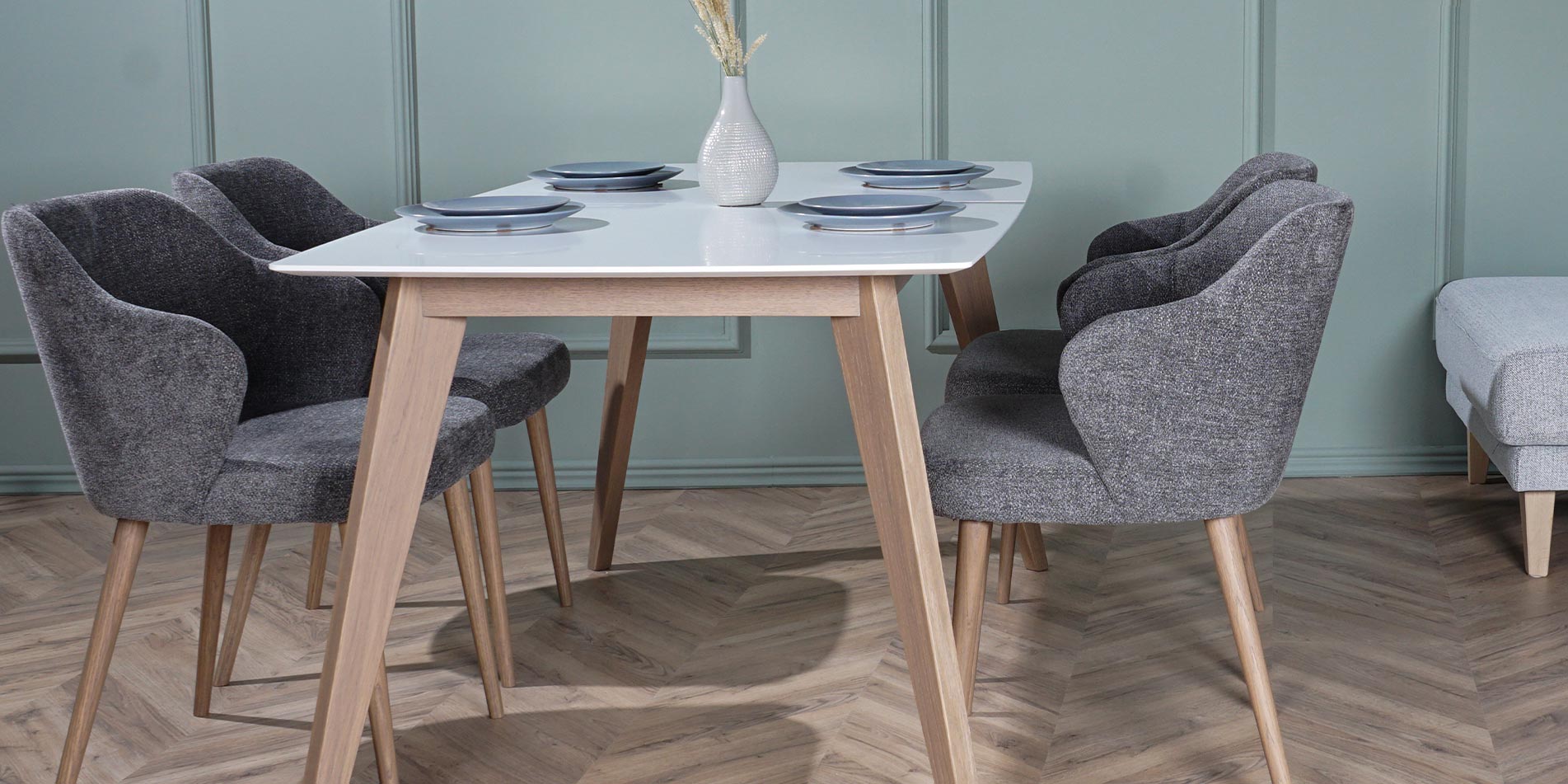 Armchairs in grey on dining table with white table top and oak legs.