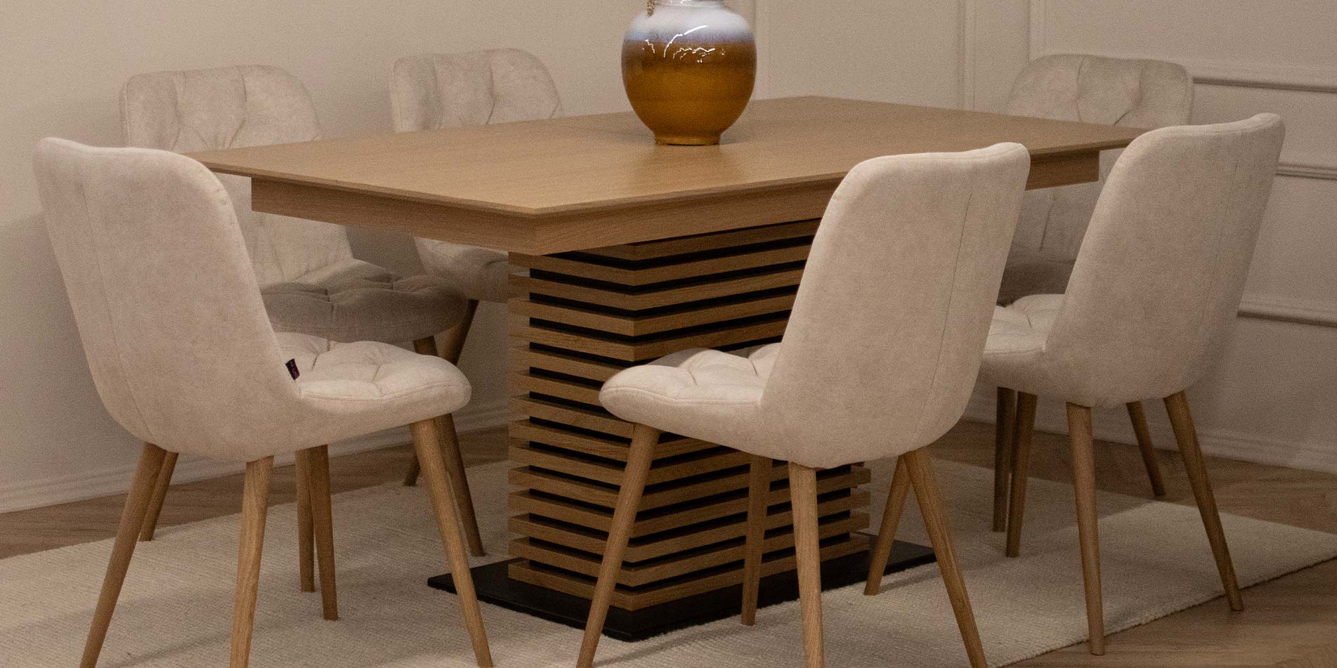 Trpezariska masa Titan od dab so sreden stolb so horizontalni letvicki i trpezariski stolici so svetlo krem mebel stof.