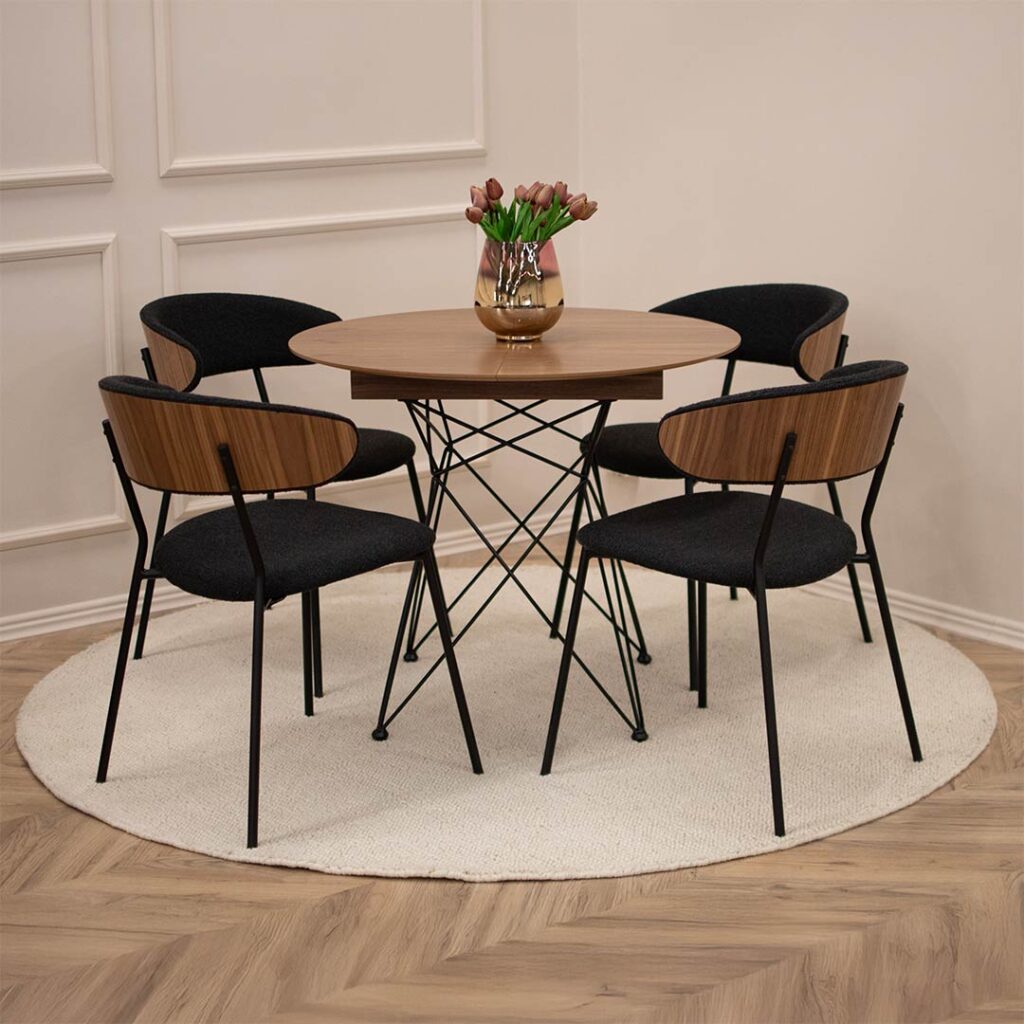 Мала кружна трпезариска маса со плотна орев и продолжеток од +35 см, со црни метални ногарки. Со столици со фурнир од орев и црн мебел штоф.