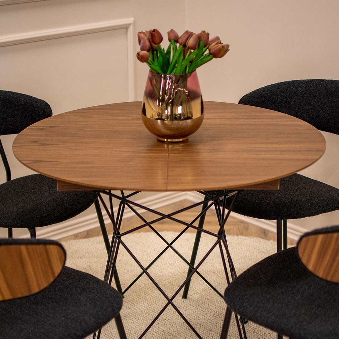 Мала кружна трпезариска маса со плотна орев и продолжеток од +35 см, со црни метални ногарки. Со столици со фурнир од орев и црн мебел штоф.