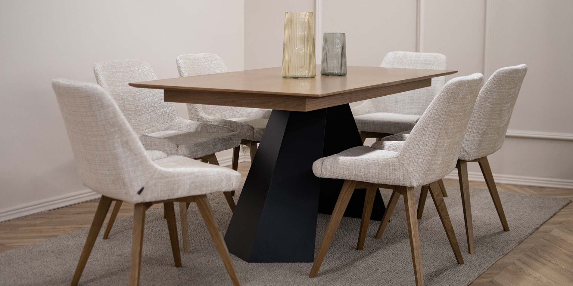 Dining table with black metal legs and oak table top, with chairs in beige upholstery and oak wood legs.