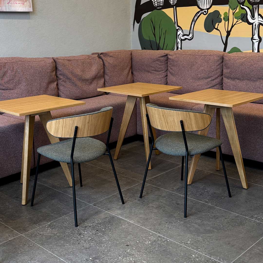Dining chairs with veneer oak back and green upholstery in coffee shop.
