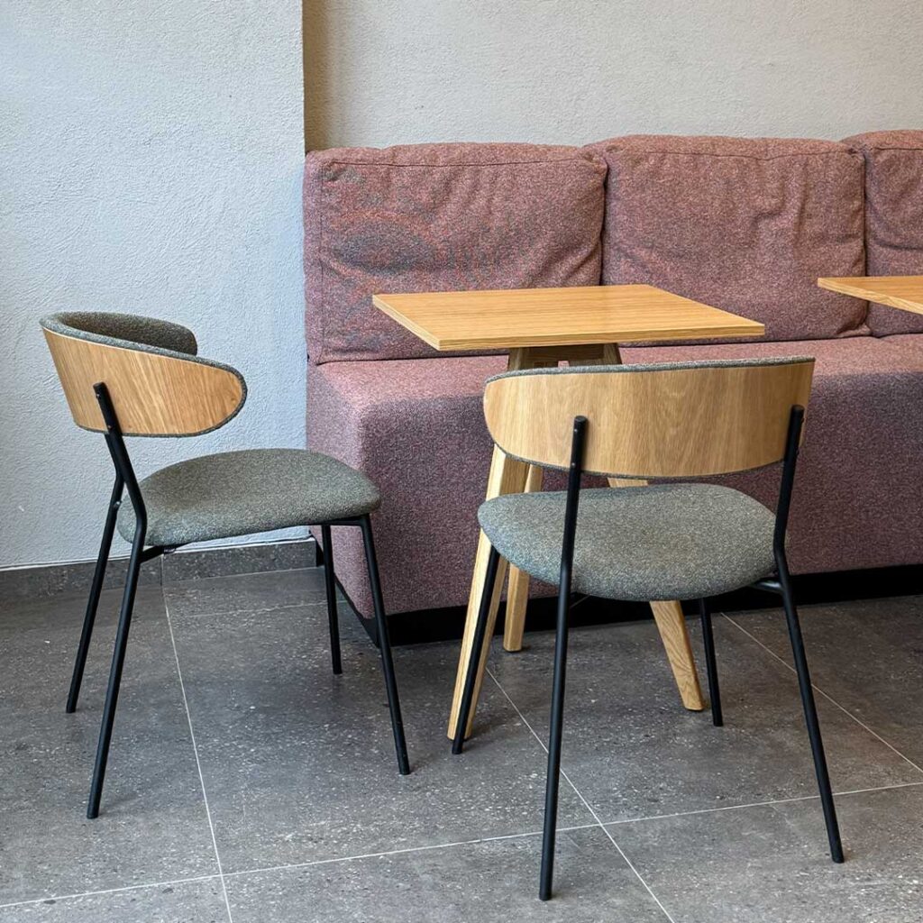 Dining chairs with veneer oak back and green upholstery in coffee shop.
