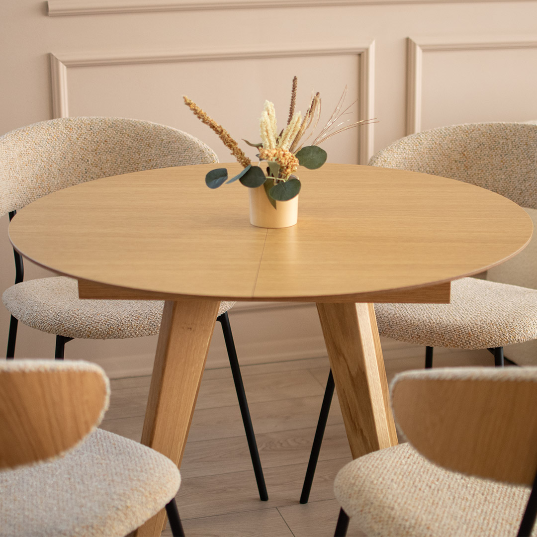 Small, round, extendable dining table made of natural oak.