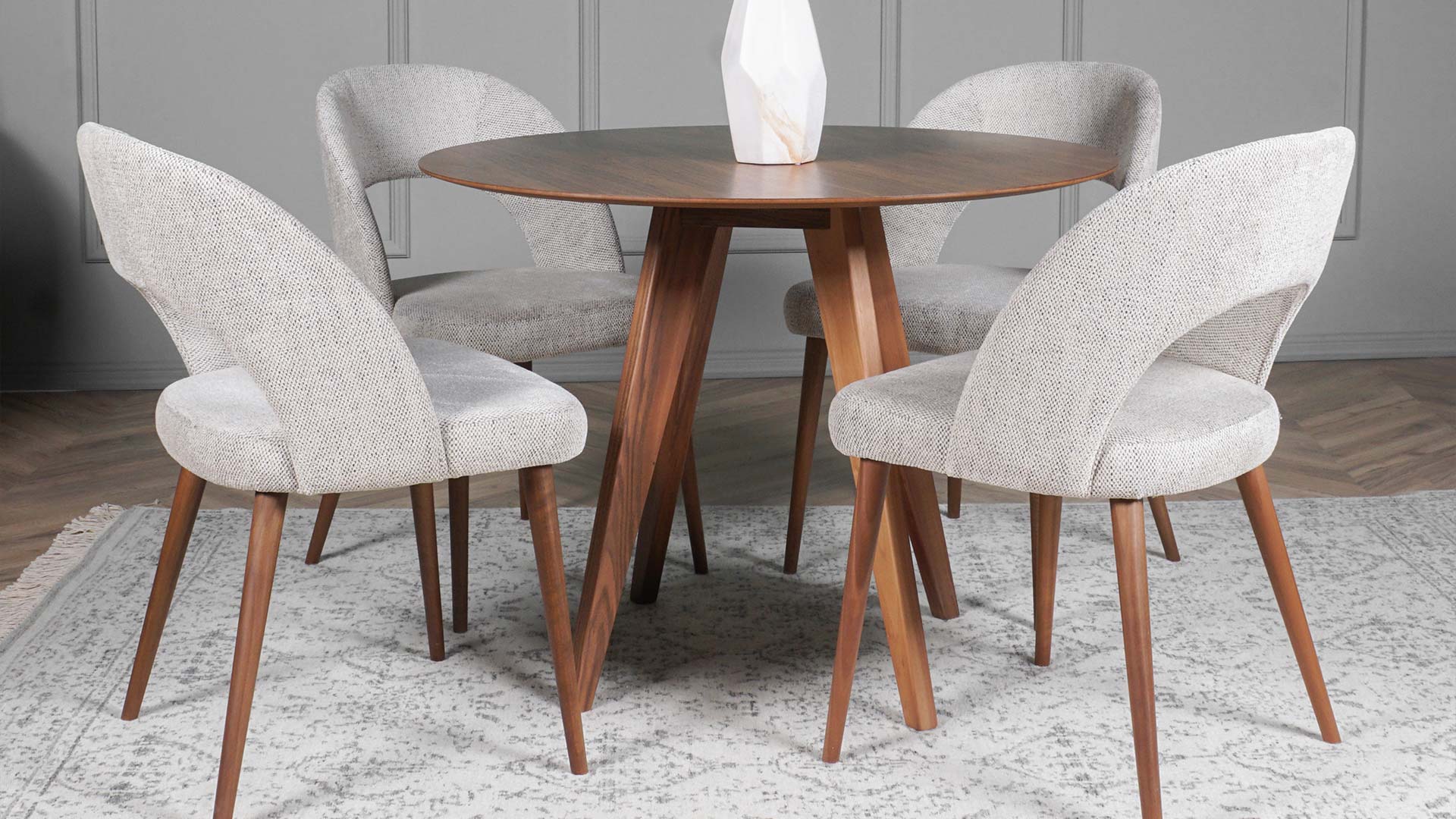 Small round dining table from walnut wood, with four dining chairs in beige upholstery.