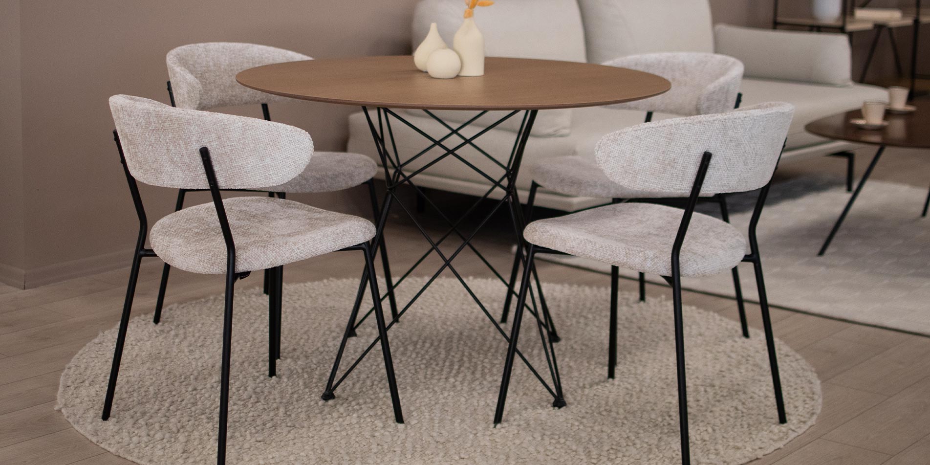 Trpezariski stolica Oasis vo krem mebel stof i crni metalni nogarki, postaveni na kruzna masa so metalni nogarki.
