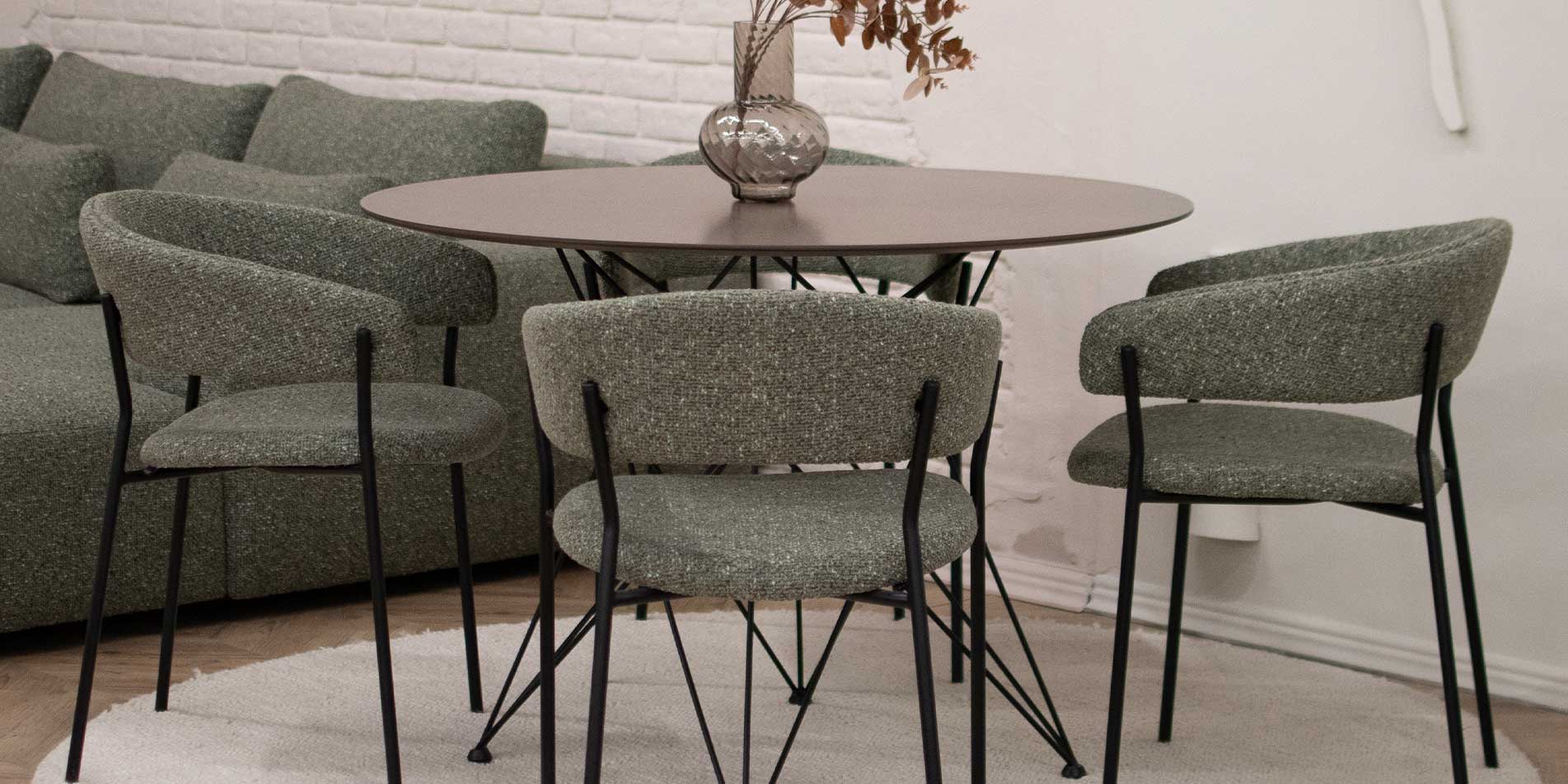 Трпезариски столици во зелен мебел штоф поставени на мала кружна маса.