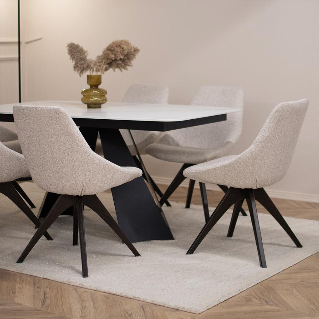 Трпезариски сет со маса со керамичка плотна и две црни метални ногарки, во комбинација со столици со светло крем мебел штоф.