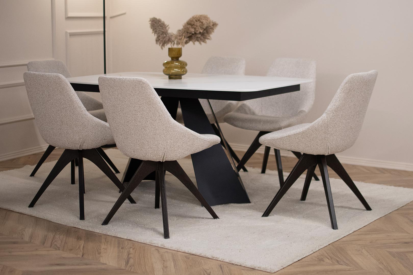 Трпезариски сет со маса со керамичка плотна и две црни метални ногарки, во комбинација со столици со светло крем мебел штоф.