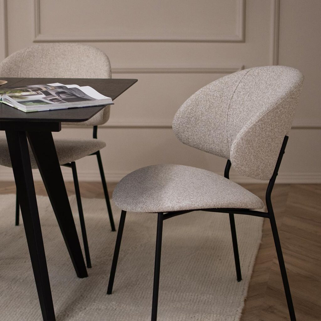 Удобна трпезариска столица во светло крем мебел штоф и црни метални ногарки.