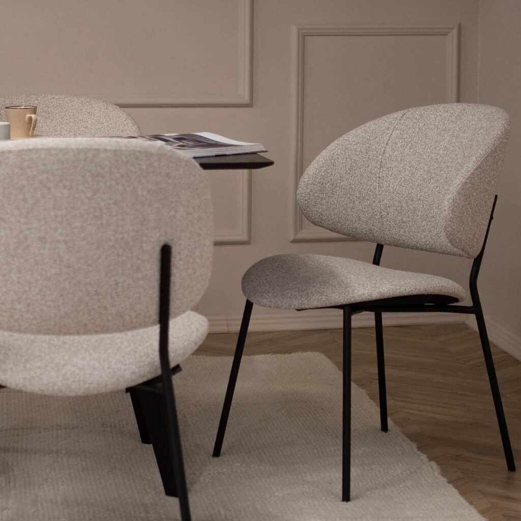Удобна трпезариска столица во светло крем мебел штоф и црни метални ногарки.