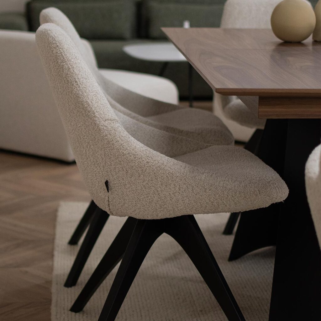 Две трпезариски столици во крем букле со црни дрвени ногарки на трпезариска маса со плотна орев.