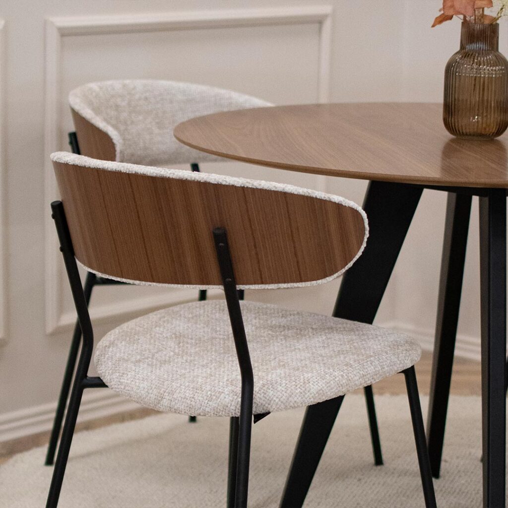 Трпезариска столица Оасис со фурниран грб од орев во комбинација со светло крем мебел штоф и црни метални ногарки.