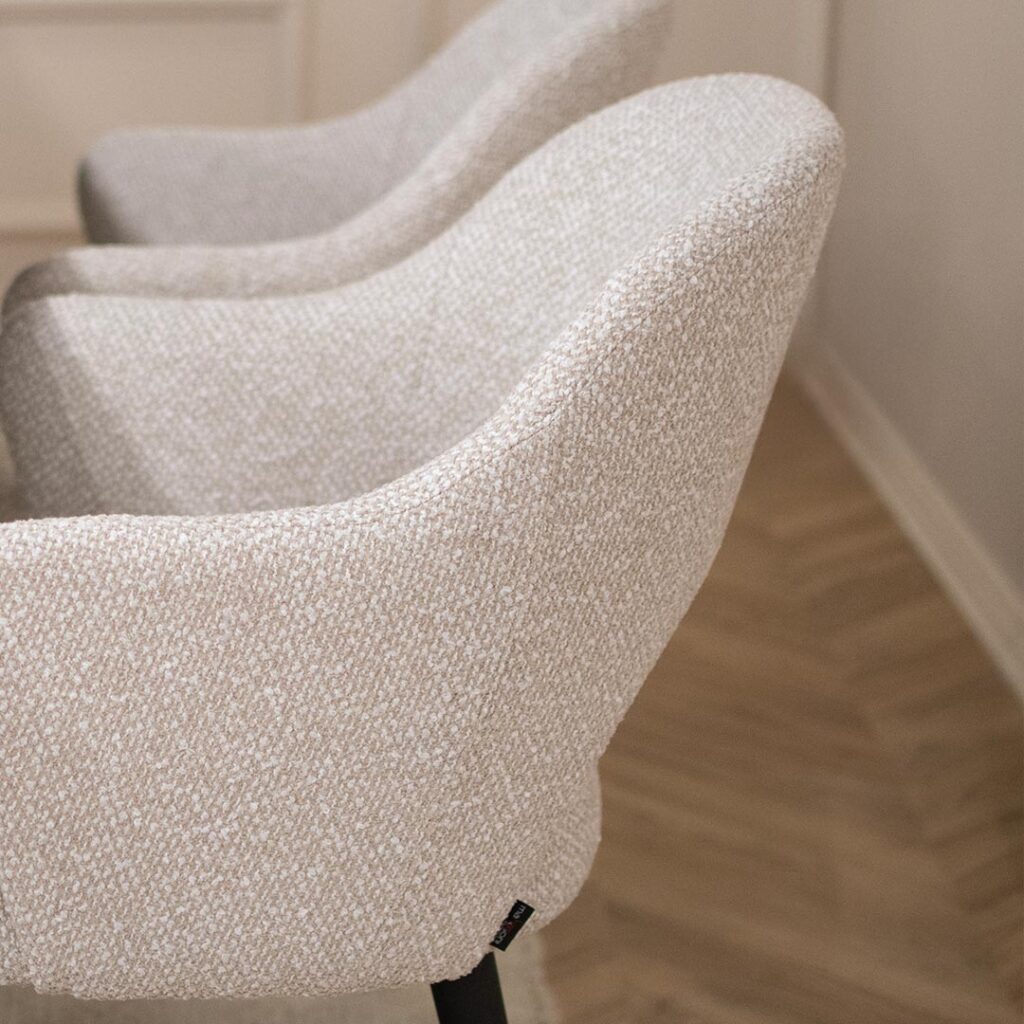 Трпезариска маса со керамичка плотна во бела боја со крем шари поставена на две црни метални ногарки во комбинација со столици со раконаслон во бел мебел штоф со црни дрвени ногарки.