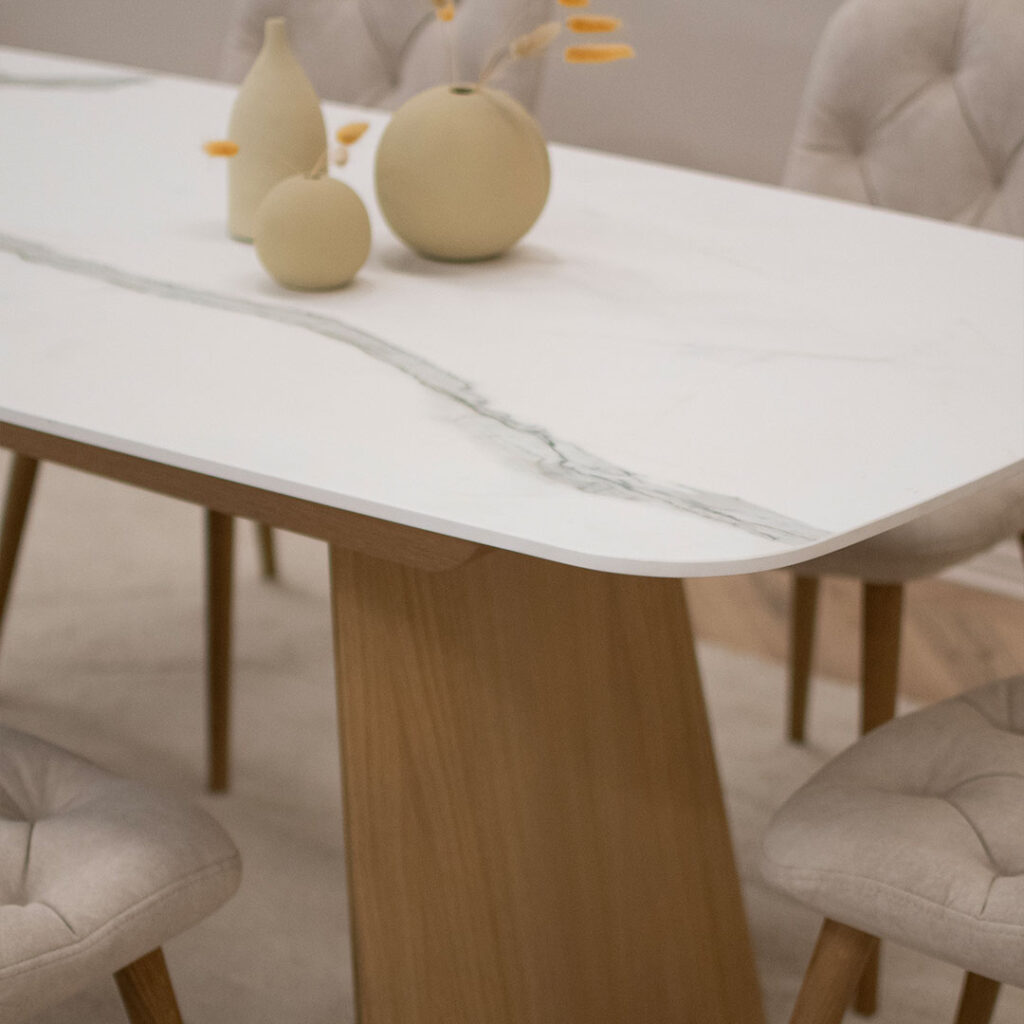 Трпезариски сет со маса со керамичка плотна и две дрвени со неправилна форма ногарки, во комбинација со 6 столици во крем велвет и дрвени даб ногарки.