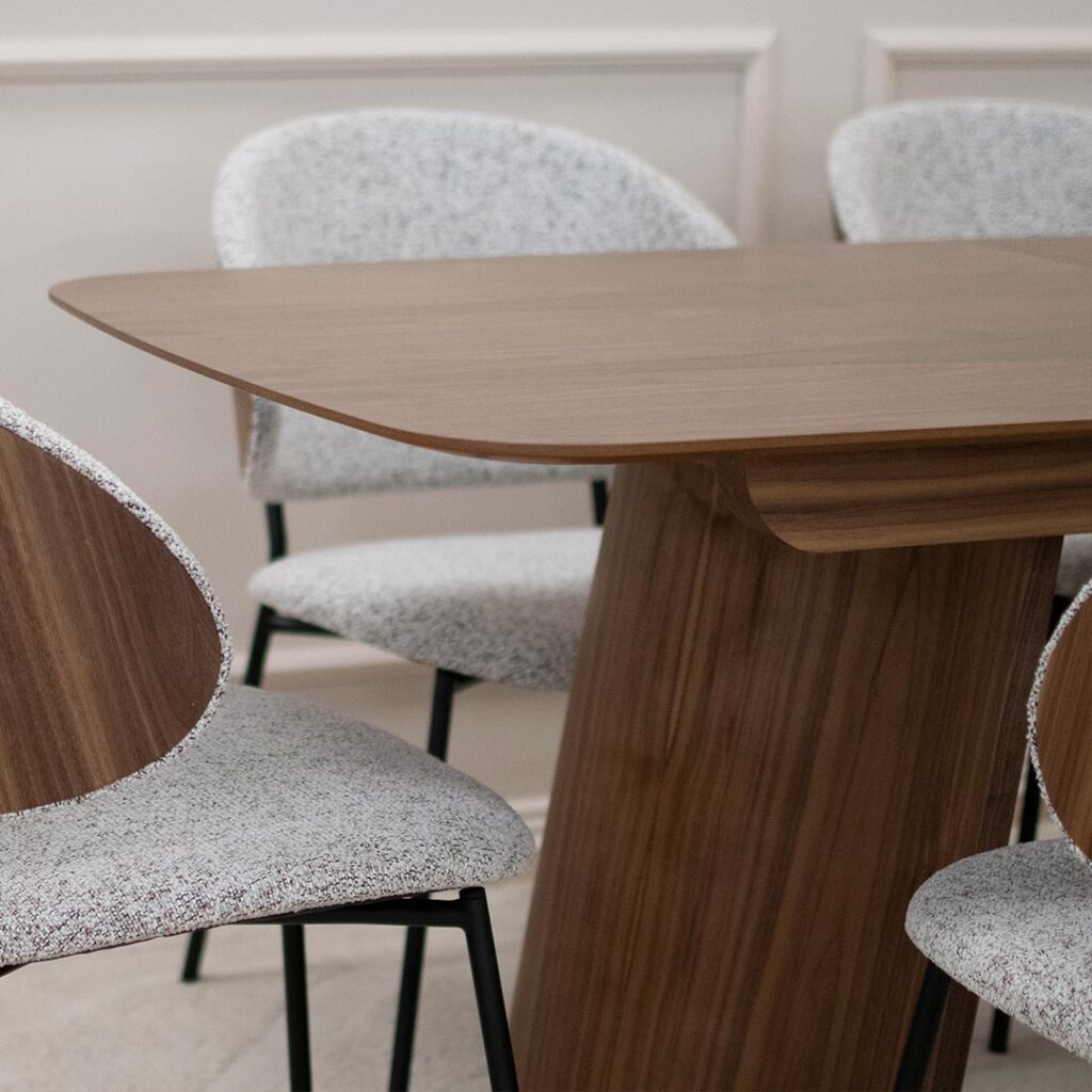 Трпезариска маса од орев со заоблена плотна и две неправилно обликувани ногарки од дрво орев.