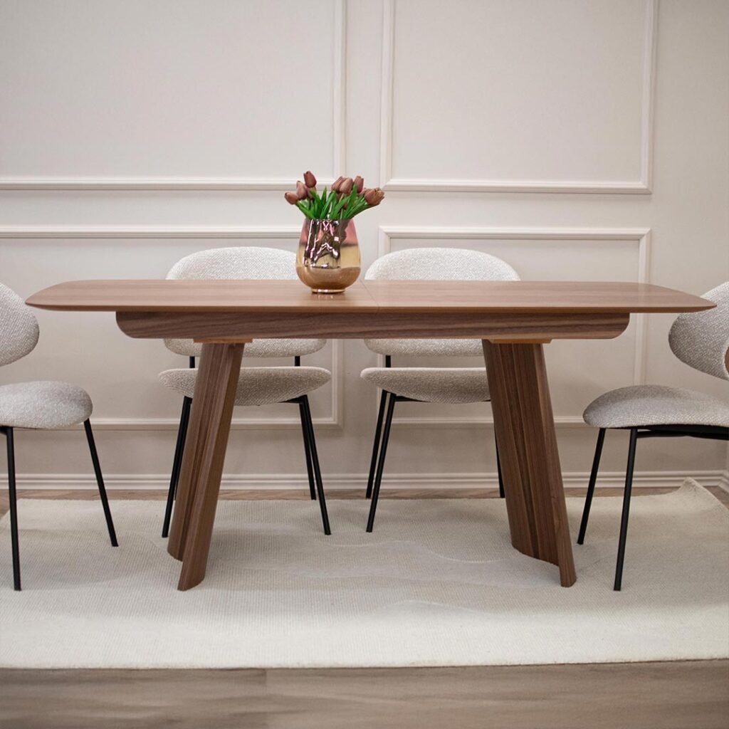 Трпезариска маса од орев со заоблена плотна и две неправилно обликувани ногарки од дрво орев.