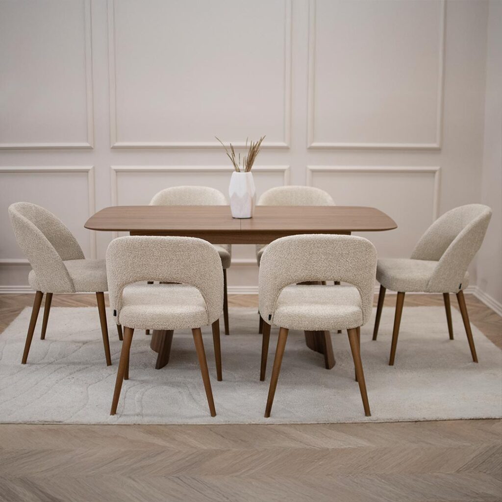 Трпезариски сет со трпезариска маса Сфера од орев со две неправилно обликувани дрвени ногарки со 6 трпезариски столици со бука кафеави ногарки и крем букле.