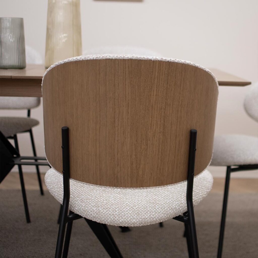 Трпезариска столица, со удобно седло во беж мебел штоф и фурнир од даб во грбот, поставена на црни елегантни метални ногарки.