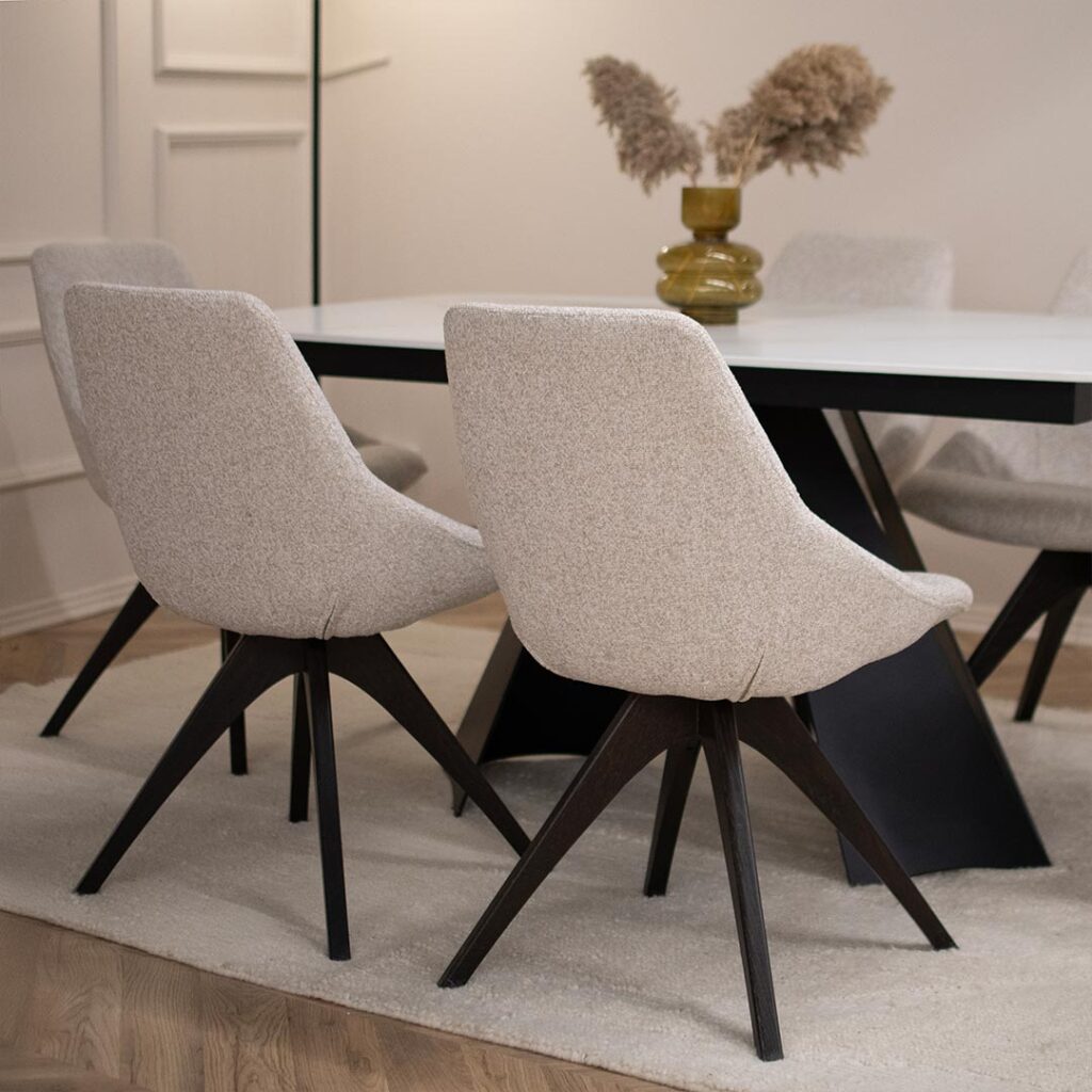 Трпезариски сет со маса со керамичка плотна и две црни метални ногарки, во комбинација со столици со светло крем мебел штоф.