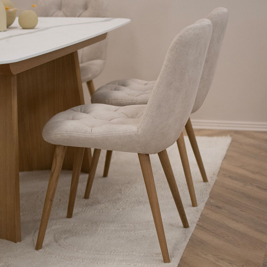 Трпезариски сет со маса со керамичка плотна и две дрвени со неправилна форма ногарки, во комбинација со 6 столици во крем велвет и дрвени даб ногарки.