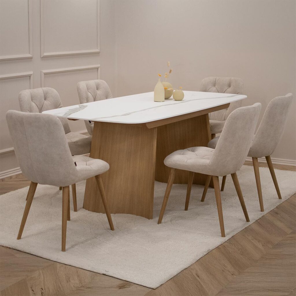 Трпезариски сет со маса со керамичка плотна и две дрвени со неправилна форма ногарки, во комбинација со 6 столици во крем велвет и дрвени даб ногарки.