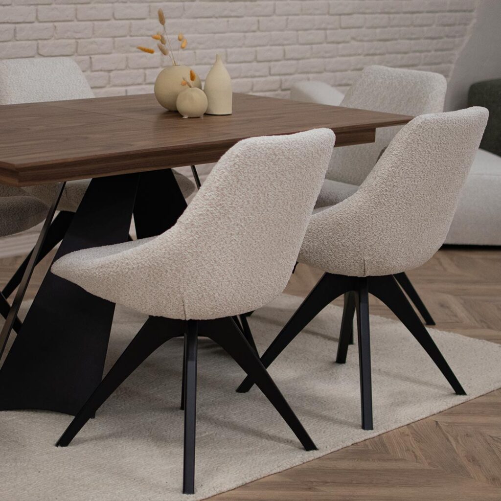 Две трпезариски столици во крем букле со црни дрвени ногарки на трпезариска маса со плотна орев.