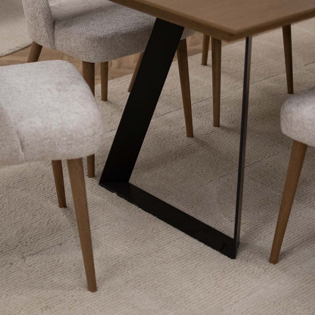 Volnen kilim vo ivory boja, postaven pod trpezariska masa Atlas.