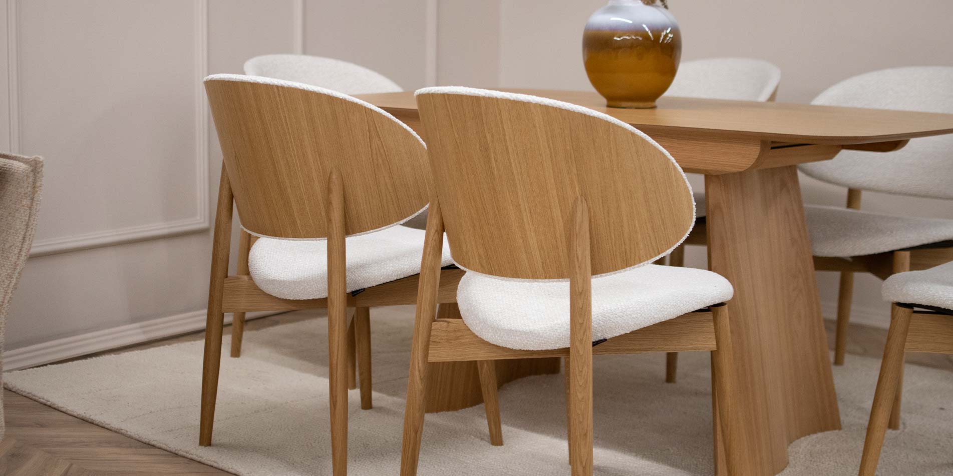 Трпезариски сет со трпезариска маса од даб натур во комбинација со столици со даб ногарки и грб од фурнир од даб, во комбинација со бел мебел штоф.