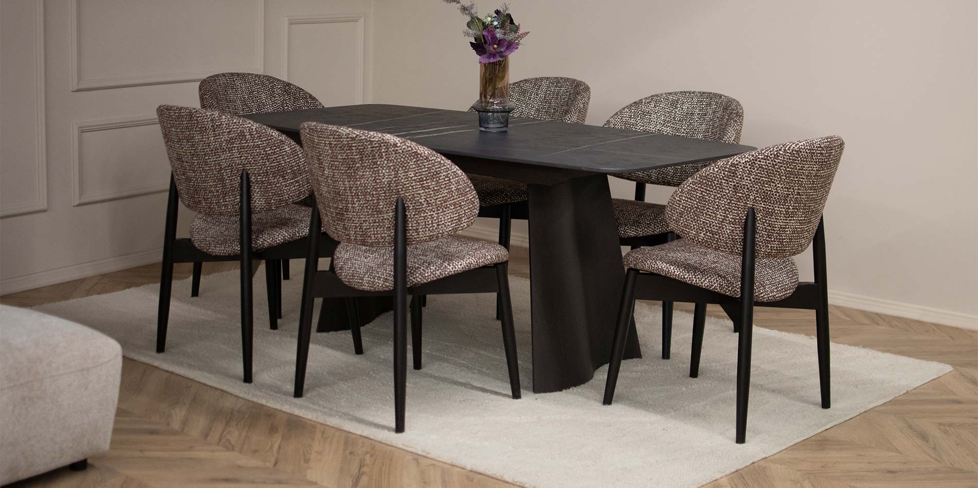 Трпезариска столица Celine со дрвени бука ногарки во црна боја и кафеав мебел штоф поставени на црна трпезариска маса.