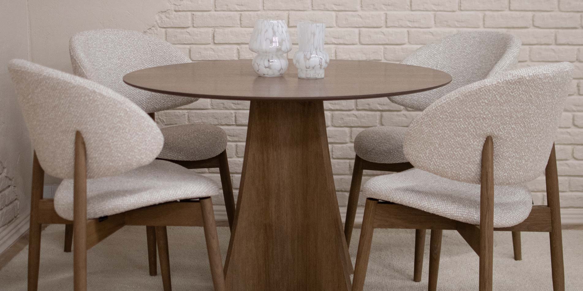 Трпезариска столица со дрвени даб ногарки и беж мебел штоф, поставени на кружна маса од дрво даб.