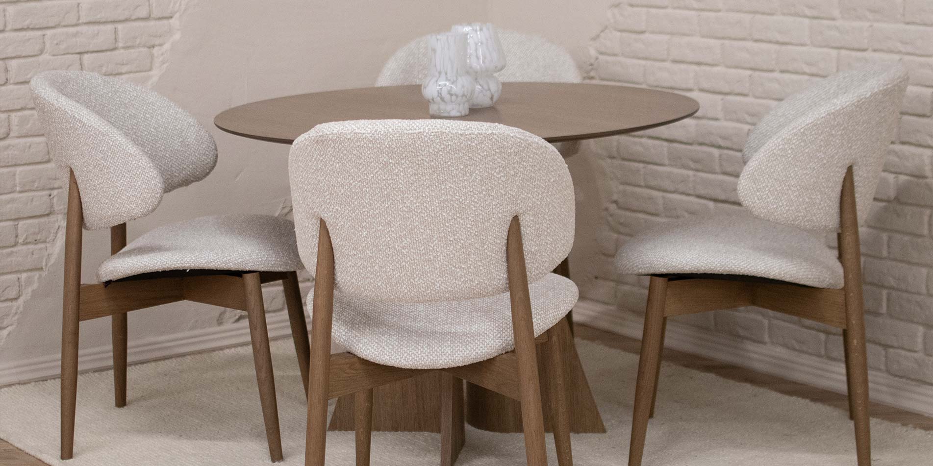 Трпезариска столица со дрвени даб ногарки и беж мебел штоф, поставени на кружна маса од дрво даб.