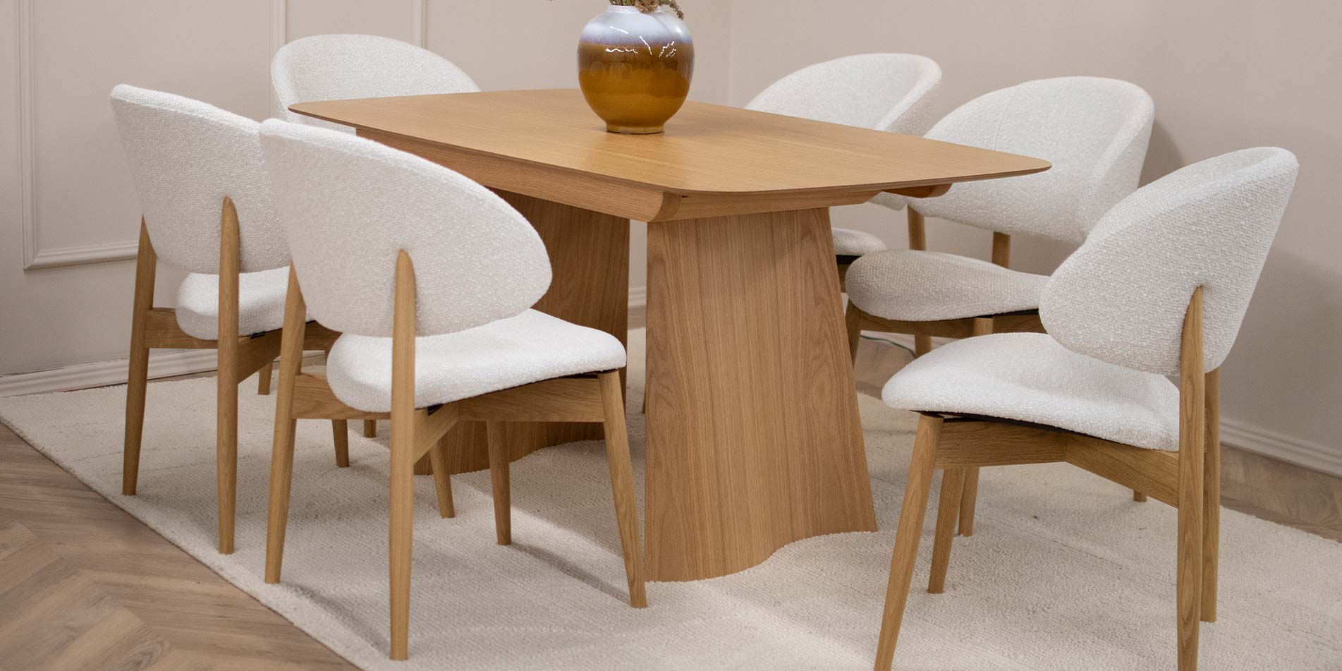 Трпезариска столица Celine со даб ногарки со светло крем мебел штоф, поставени на маса од дрво даб натур.