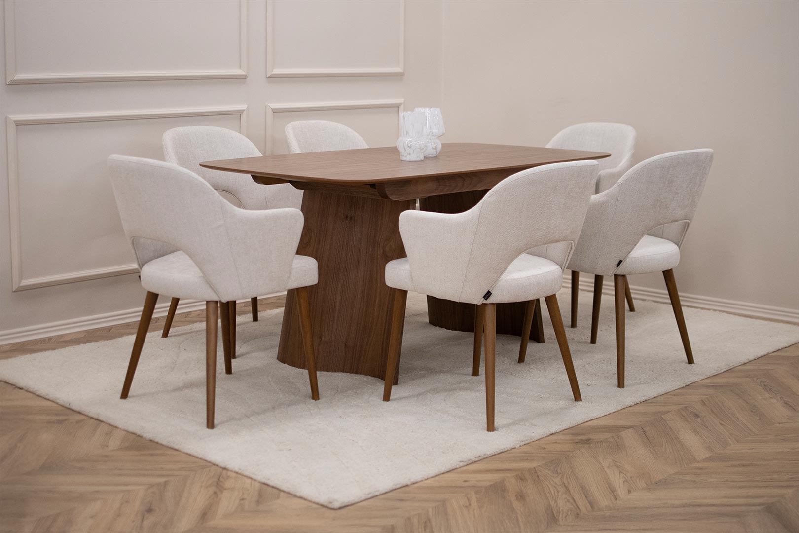 Трпезариски сет со маса со заоблена плотна орев и две неправилна форма ногарки, со трпезариски столици со раконаслон со бука кафеава боја ногарки и светло крем мебел штоф.