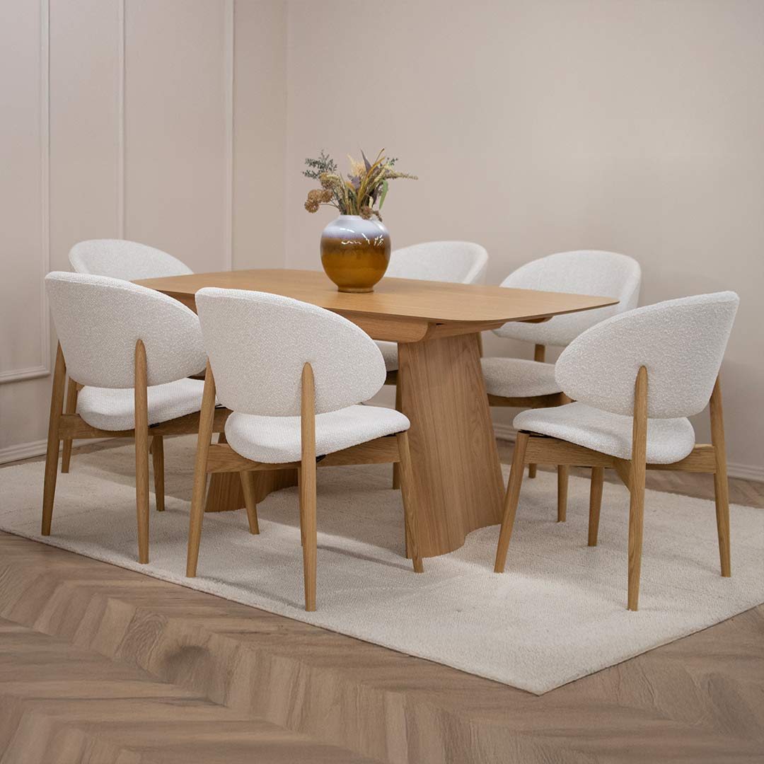 Трпезариска столица Celine со даб ногарки со светло крем мебел штоф, поставени на маса од дрво даб натур.