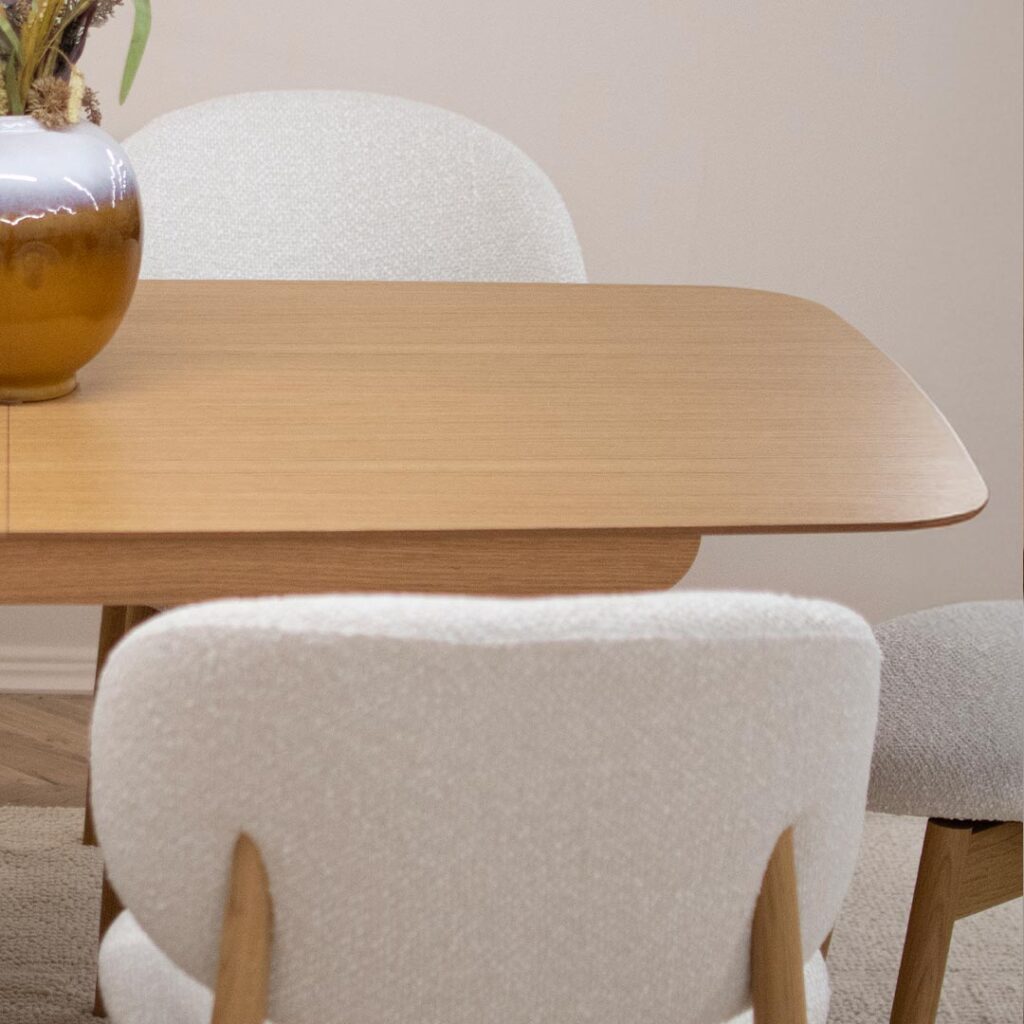 Трпезариски сет со маса од дрво даб со заоблени агли и две неправилна форма ногарки, со трпезариски столици во бел мебел штоф и даб натур боја ногарки.