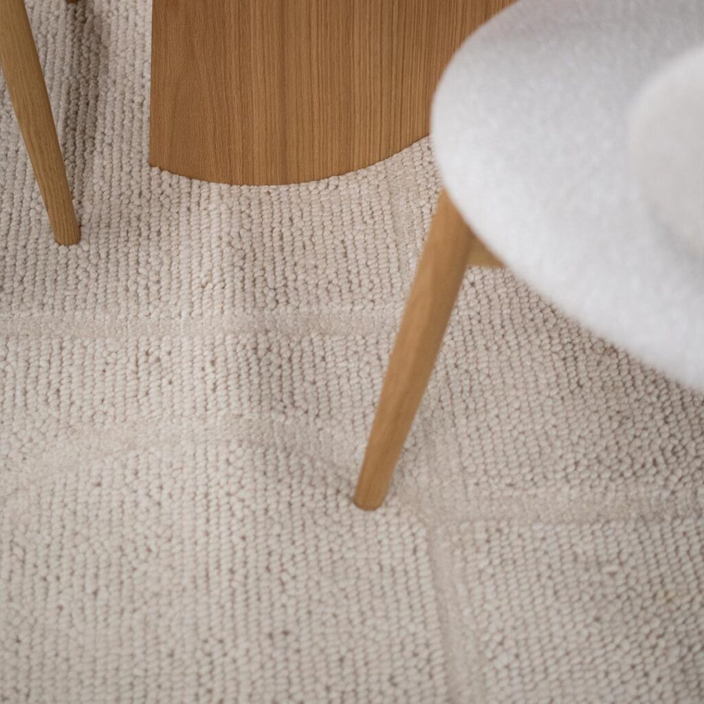 Волнен килим со неправилни ткаени форми во бела боја на природна волна.