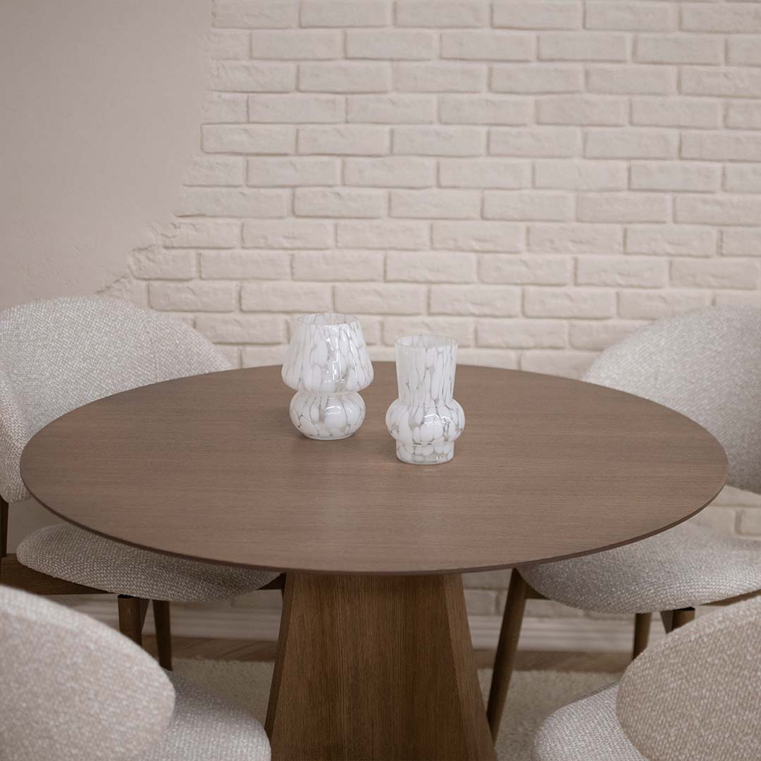 Round Astra dining table in oak with central base and upholstered dining chairs in light fabric, modern dining room interior