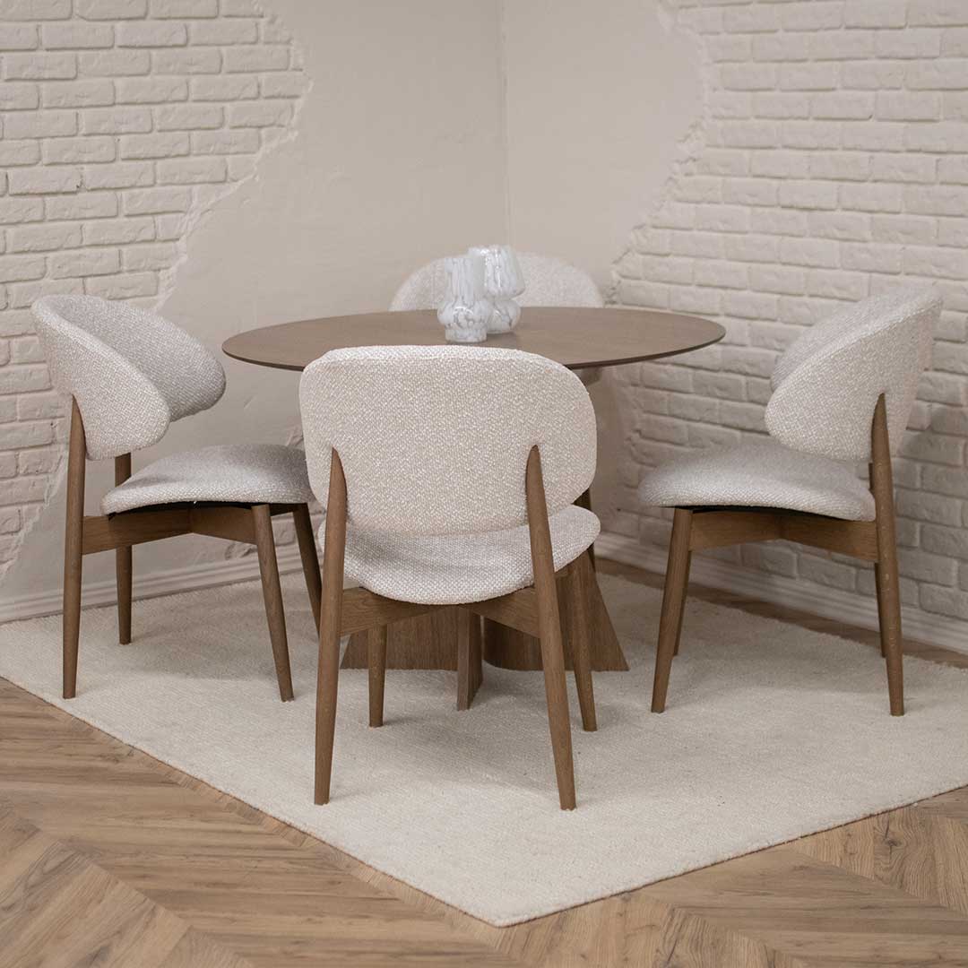Round Astra dining table in oak with central base and upholstered dining chairs in light fabric, modern dining room interior