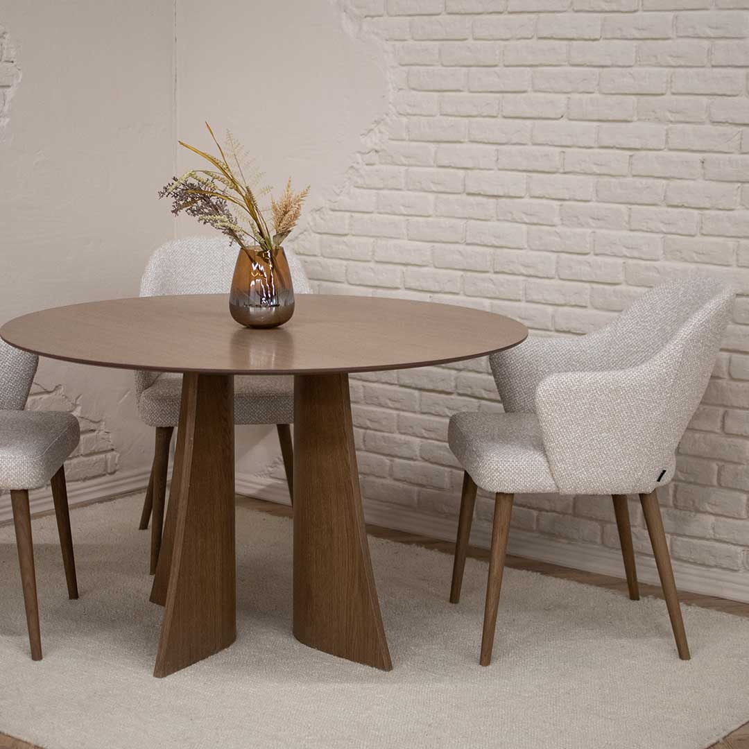 Round Astra dining table in oak with central base and upholstered dining chairs in light fabric, modern dining room interior