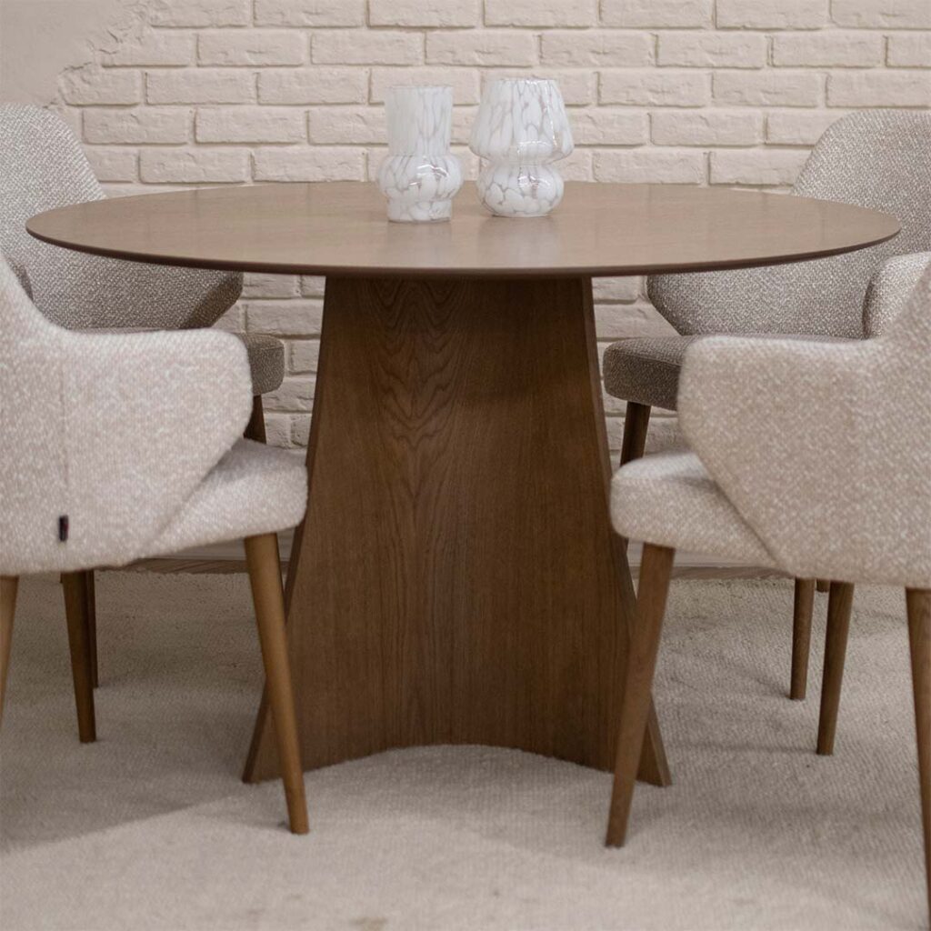 Round Astra dining table in oak with central base and upholstered dining chairs in light fabric, modern dining room interior