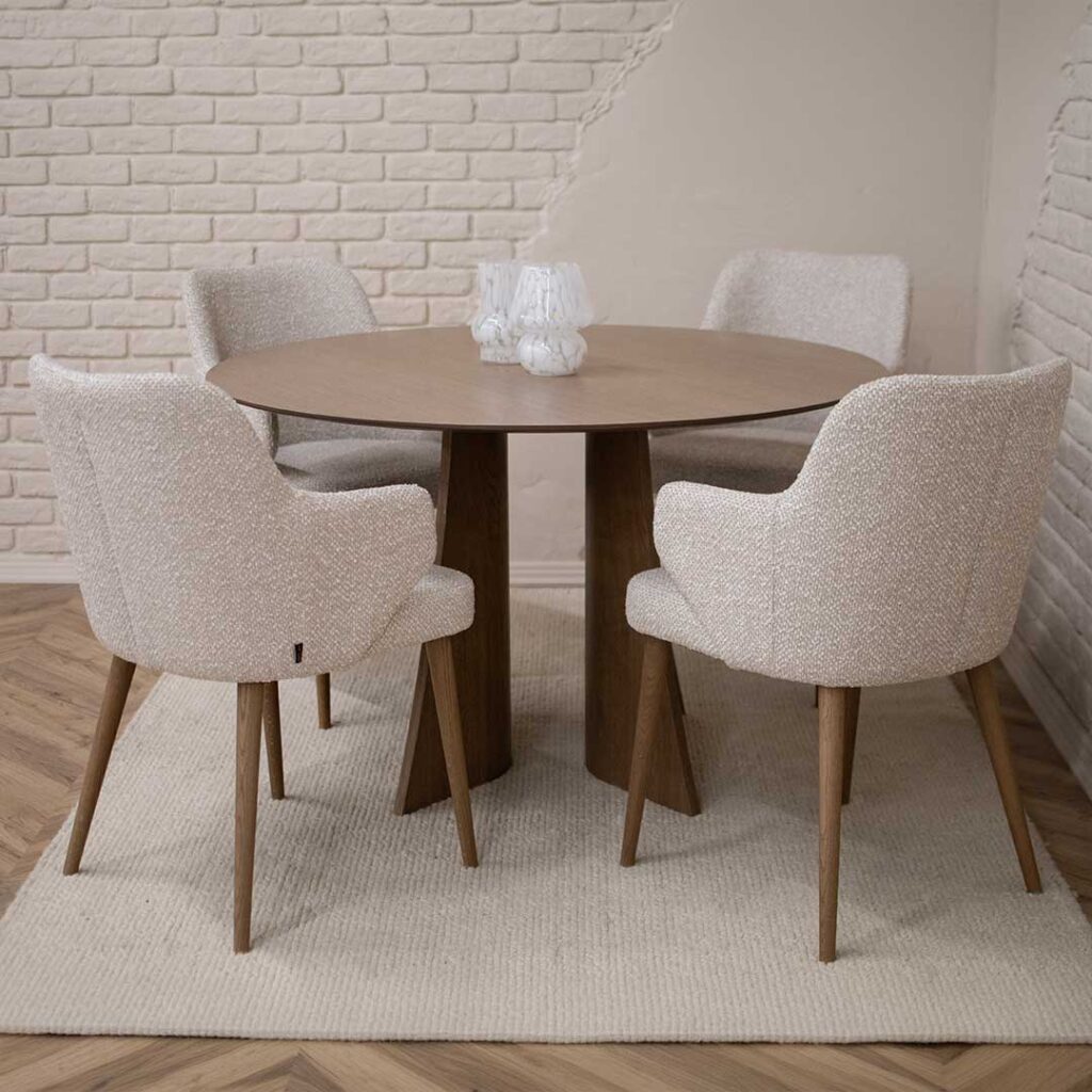 Round Astra dining table in oak with central base and upholstered dining chairs in light fabric, modern dining room interior