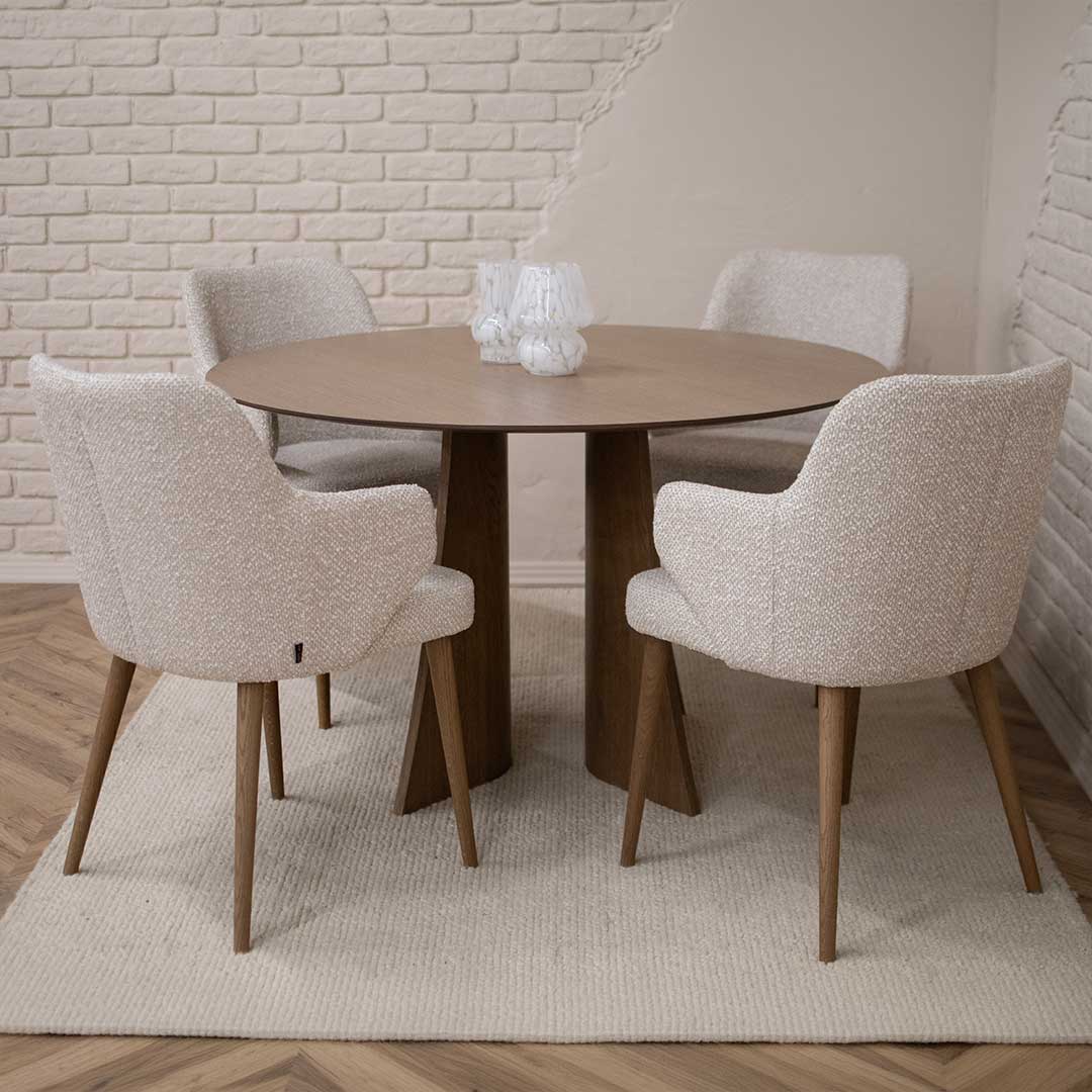 Round Astra dining table in oak with central base and upholstered dining chairs in light fabric, modern dining room interior