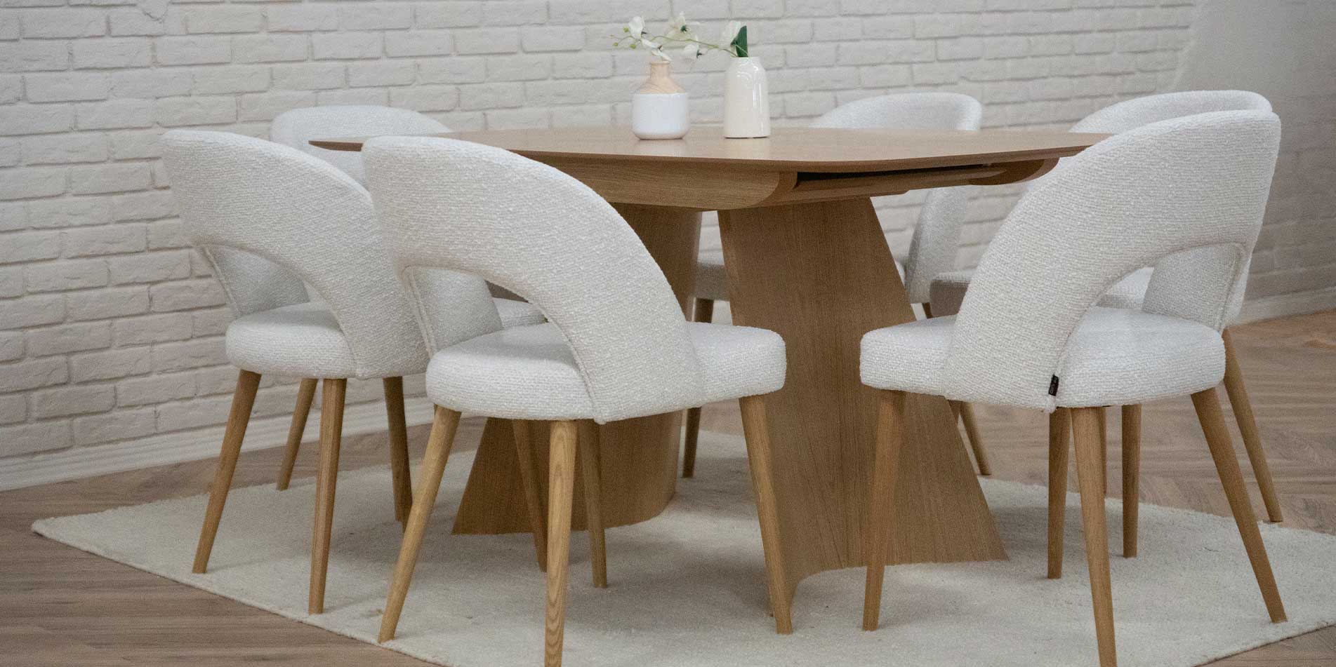 Trpezariska masa od dab natur, so dve nepravilna forma nogarki, so beli trpezariski stolici.