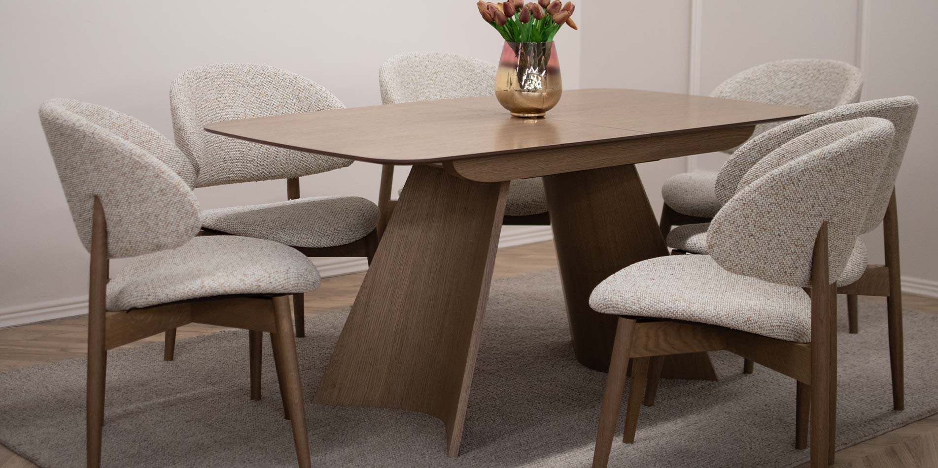 Трпезариска маса Orbis од даб со заоблени ногарки и столици Celine во светол мебел штоф, модерен трпезариски сет во топол ентериер.