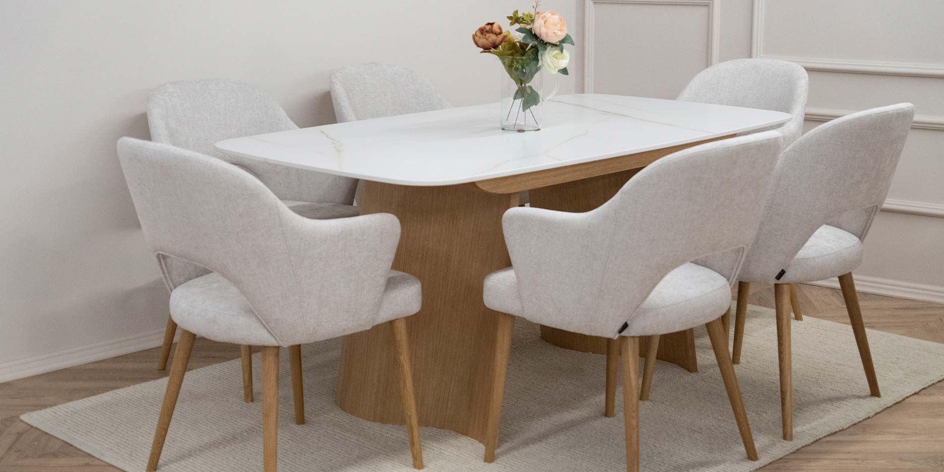 Dining armchairs with oak legs and white upholstery on dining table with ceramic table top.
