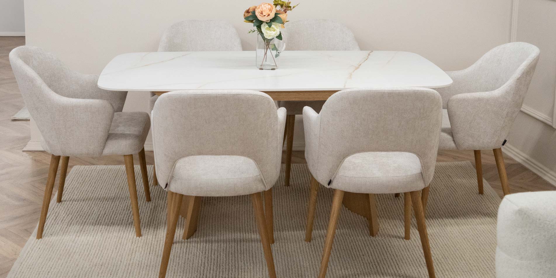 Dining armchairs with oak legs and white upholstery on dining table with ceramic table top.