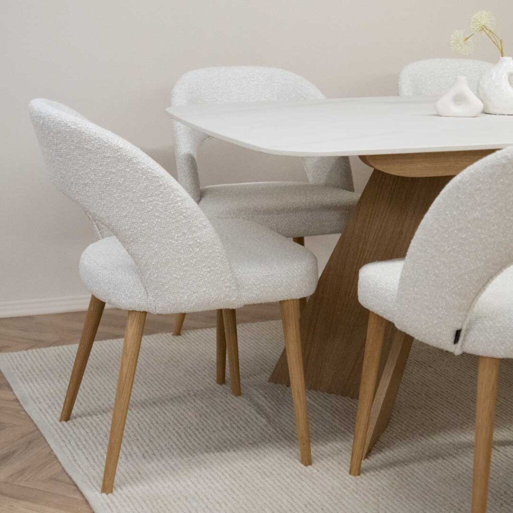 Trpezariska masa Orbis so plotna Laminam vo bela boja i nepravilna forma nogarki od dab, so stolici Aurora so dab nogarki i bel mebel stof.