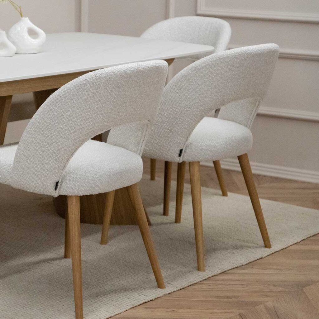 Trpezariska masa Orbis so plotna Laminam vo bela boja i nepravilna forma nogarki od dab, so stolici Aurora so dab nogarki i bel mebel stof.